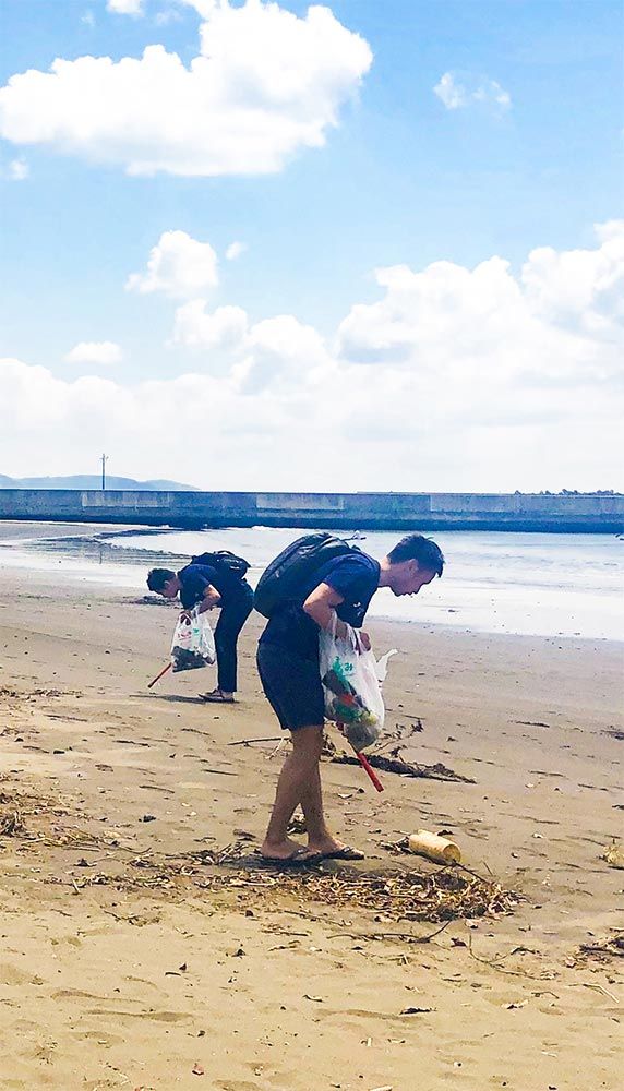 Two staff members cleaning up a beach as part of a volunteer event.