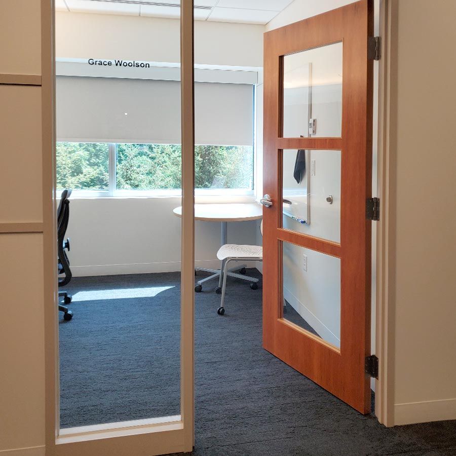 View of Grace’s office with open door, guess table and chair, and window to the outside.
